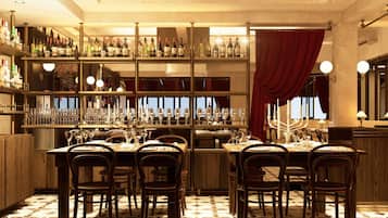 A bar area with multiple shelves of bottles, a dining table set with chairs, and a patterned floor.