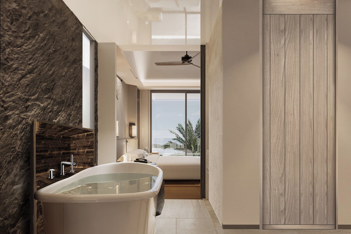 A modern bathroom with a freestanding bathtub, a large window with a view, and a wooden door.