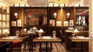A restaurant interior with wooden paneling, tables set with wine glasses, and a bar area with bottles.