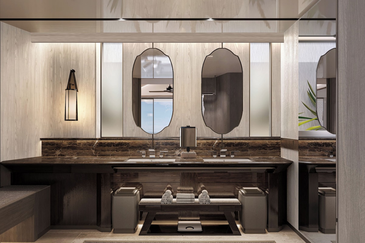 A modern bathroom with a large mirror, a wall-mounted light, and a marble countertop.