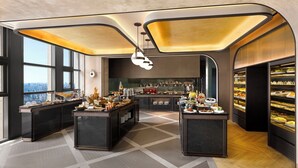 Una barra de desayuno moderna con vistas a la ciudad, una zona de cocina y un refrigerador exhibidor.