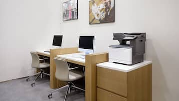 A modern office space with three desks, each with a computer and a printer.