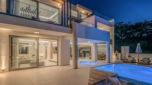 A modern multi-story house with a swimming pool, glass doors, and outdoor seating. - Luxurious Villa Selestine - With Private Pool (Mylopotamos)