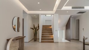 A modern interior with a staircase, a wooden bench, and a potted plant. - Luxurious Villa Selestine - With Private Pool (Mylopotamos)
