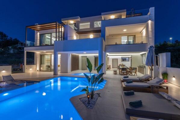 Uma casa moderna de dois andares com piscina, área de estar externa e espaço para refeições.