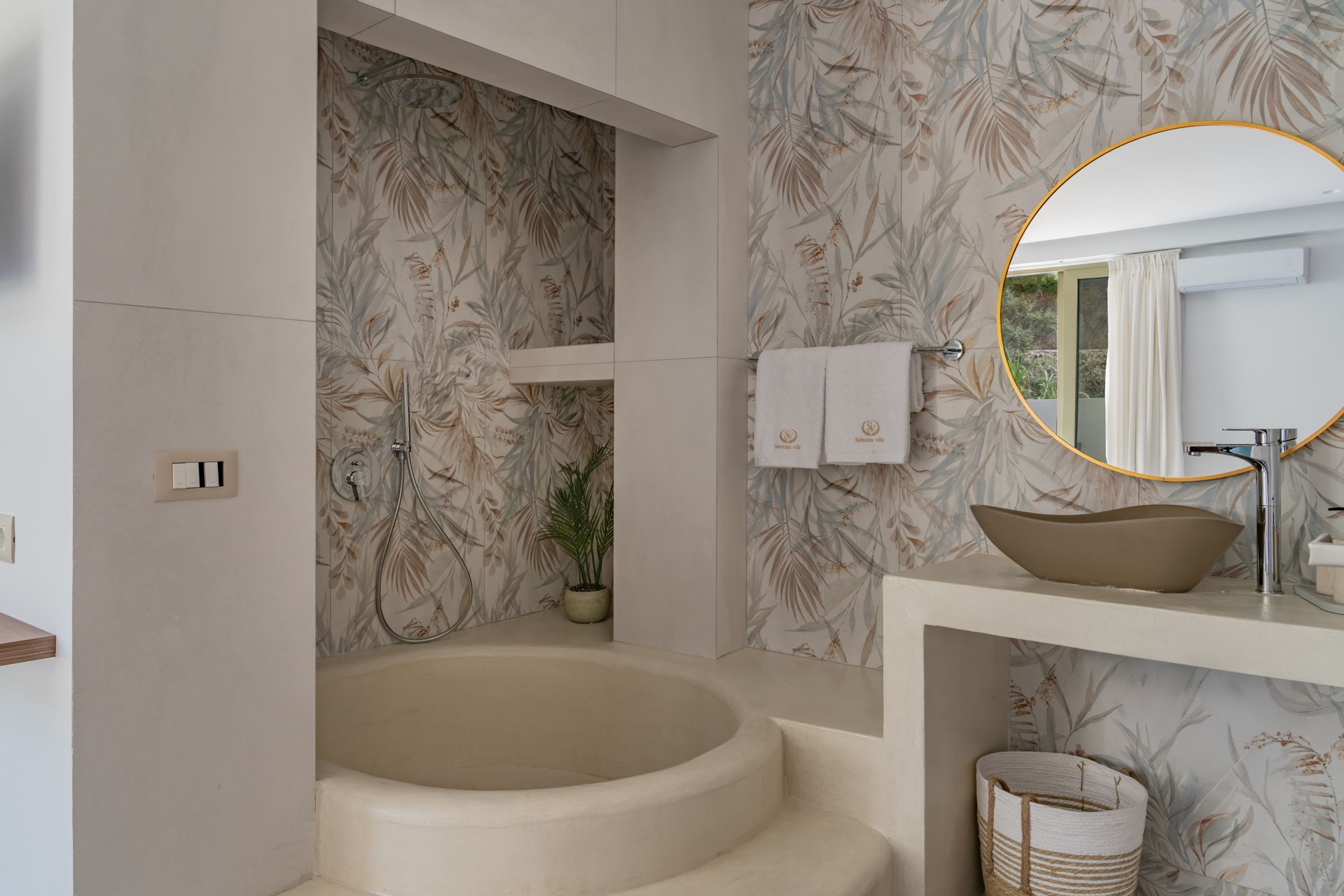 A modern bathroom with a freestanding bathtub, a round mirror, and a large sink.