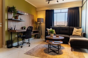 A modern living room with a sofa, a desk, a chair, and a coffee table. - View of the Cordillera Blanca | Design & Comfort | Garage | Elevator (Huaraz)