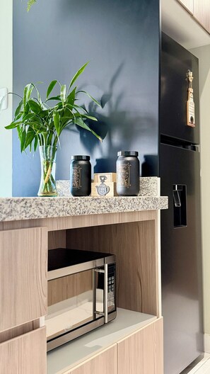 A kitchen with a modern design, featuring a dark blue backsplash, a stainless steel refrigerator, a microwave, and a plant on the counter. - View of the Cordillera Blanca | Design & Comfort | Garage | Elevator (Huaraz)