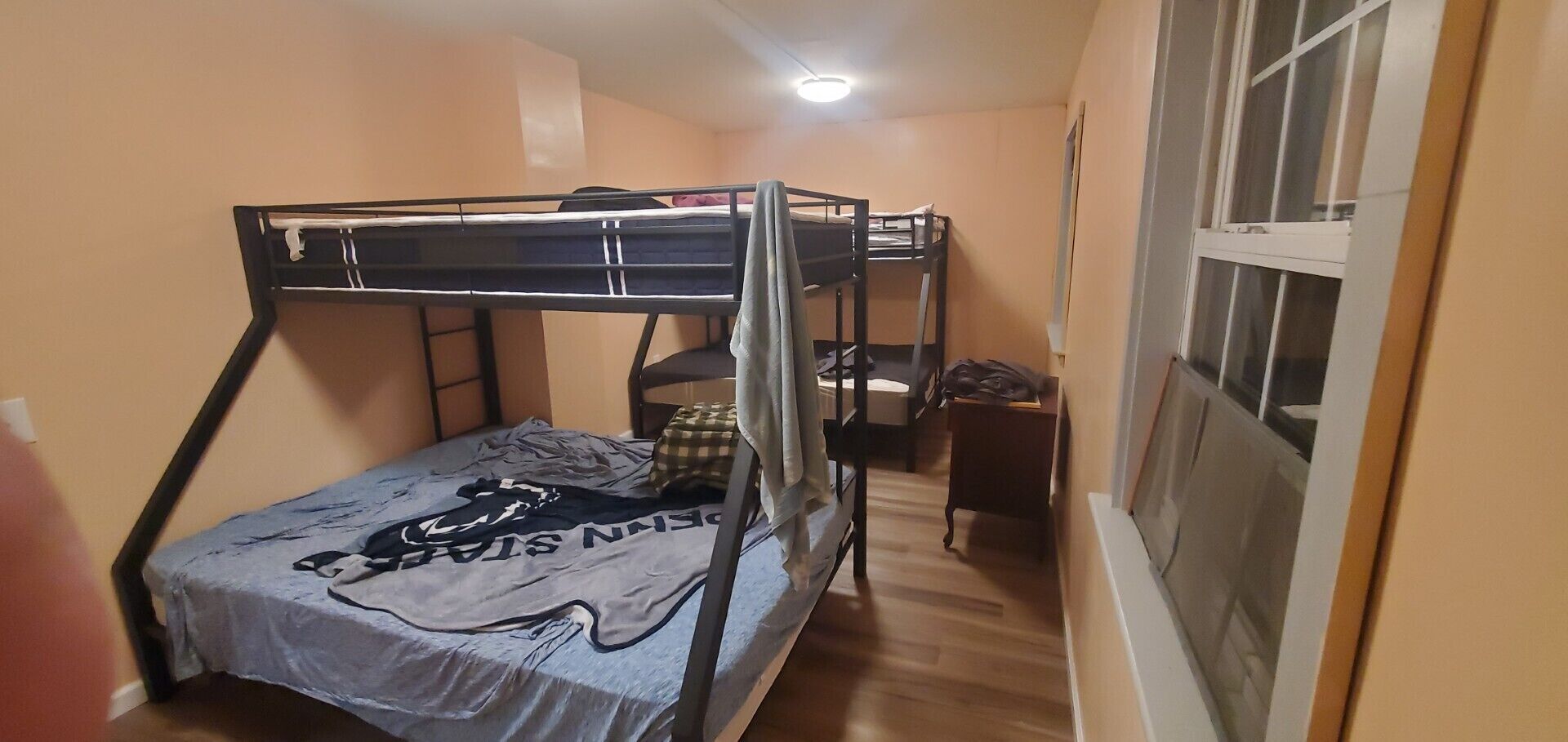 Una habitación pequeña con cama individual, literas, escritorio y silla.