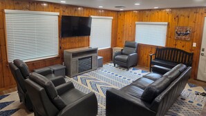 Una sala de estar acogedora con sofá, sillones, televisión y chimenea.