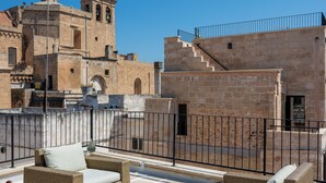Terrassa al terrat amb mobles de vimetes i vista a edificis de pedra històrics.