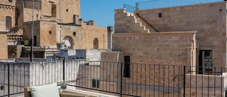 Terrassa al terrat amb mobles de vimetes i vista a edificis de pedra històrics.