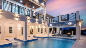 Una piscina interior moderna con diseño de varios niveles, múltiples zonas de estar y una escalera que lleva a niveles superiores.