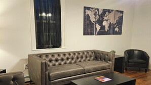 A living room with a leather sofa, a black coffee table, a black armchair, and a world map on the wall.