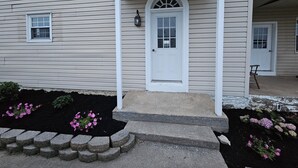A two-story house with a front porch, a white door, and a small window.