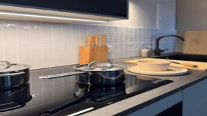 Een moderne keuken met een Bosch inductiekookplaat, een houten snijplank en een witte kom op het aanrecht.