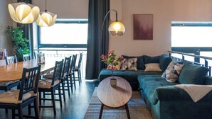 Een moderne woonkamer met een eethoek, grote ramen en een balkon.