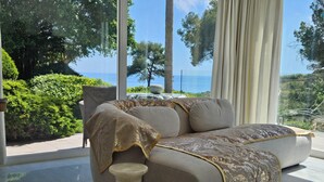 Un salón moderno con sofá, una mesita auxiliar y vista al mar a través de amplios ventanales.