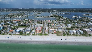Vue aérienne d’une ville côtière avec un port de plaisance, une plage et des immeubles résidentiels.