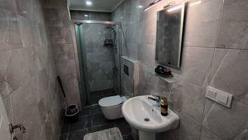 Une salle de bain moderne avec une douche à parois de verre, un lavabo blanc et un miroir au-dessus.