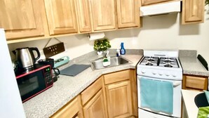 A kitchen with wooden cabinets, a microwave, a stove, and a sink.