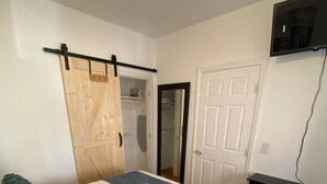 A bedroom with a bed, a wardrobe, a desk, and a TV. - Comfy Getaway Private Apt Studio (West New York)