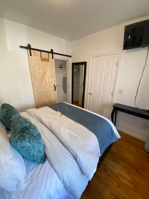 Ein Schlafzimmer mit Bett, Kleiderschrank, Schreibtisch und Fernseher.