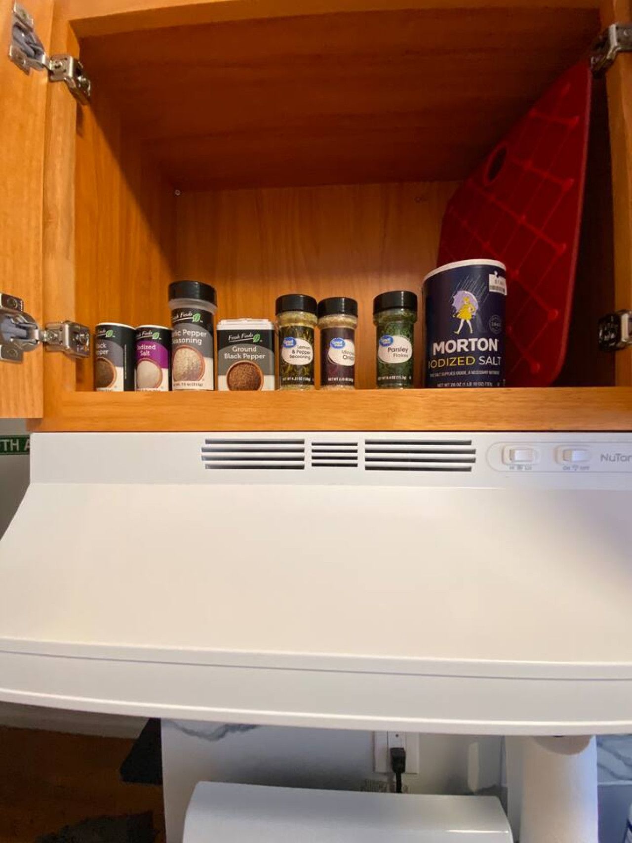 A kitchen cabinet with various spice containers.