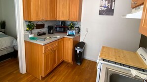 A compact kitchen with wooden cabinets, a microwave, a coffee maker, and a small sink.