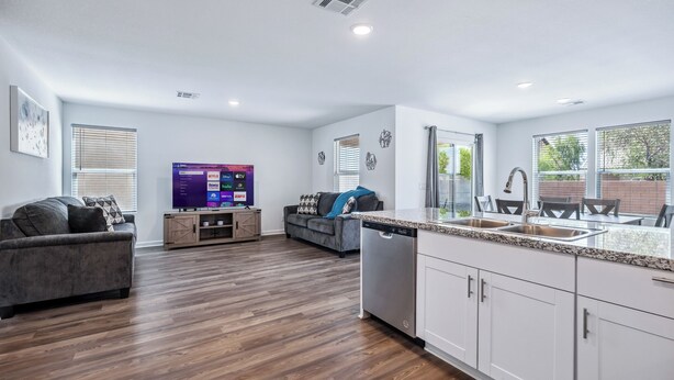A modern living room with a grey sofa, a flat-screen TV, and a wooden cabinet. - New Build Close to River & Golf! (Fort Mohave)