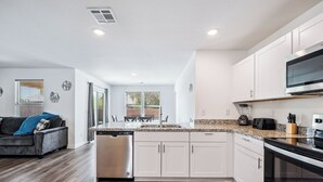 A modern kitchen with white cabinets, a stainless steel dishwasher, and a black oven. - New Build Close to River & Golf! (Fort Mohave)