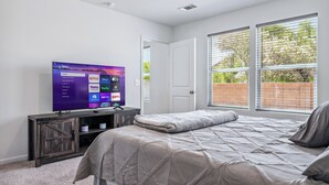 A bedroom with a bed, a TV on a stand, a door, and a window with blinds. - New Build Close to River & Golf! (Fort Mohave)