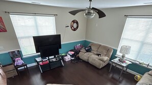 A living room with a flat-screen TV, two sofas, a ceiling fan, and a clock on the wall. - This property is not available any longer sorry for inconvenience (Moncks Corner)