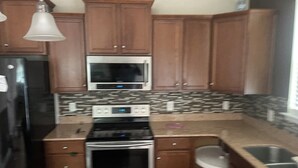A kitchen with wooden cabinets, a stainless steel refrigerator, a microwave, an oven, and a sink. - This property is not available any longer sorry for inconvenience (Moncks Corner)