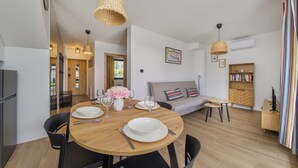 A modern living room with a dining table set for two, a sofa, a bookshelf, and a TV stand. - Apartamenty Sun & Snow Bałtycka Oaza (Wladyslawowo)