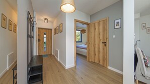 A hallway with wooden flooring, a bench, a door with a mirror, and framed pictures on the walls. - Apartamenty Sun & Snow Bałtycka Oaza (Wladyslawowo)