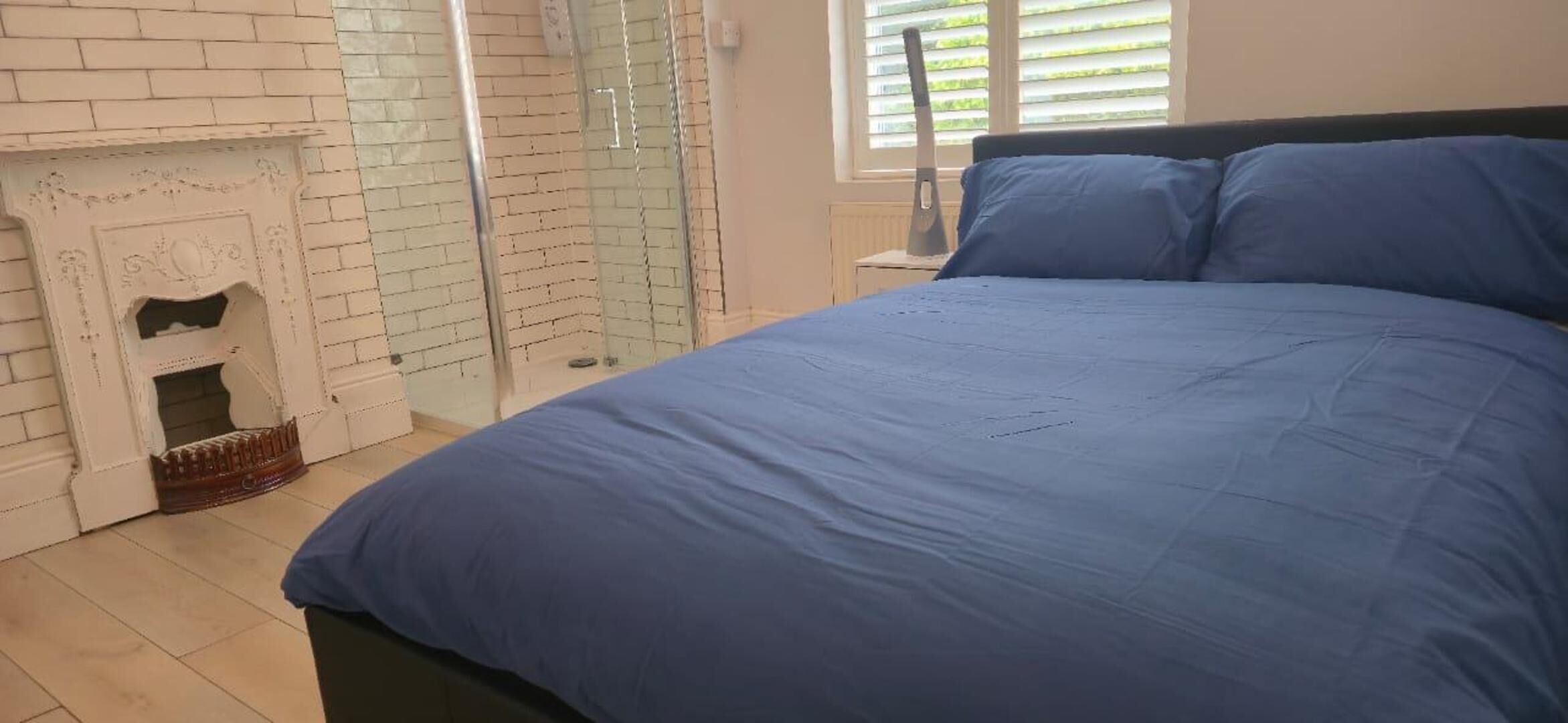 Un dormitorio con una cama grande, una chimenea de ladrillo y una cabina de ducha de vidrio.