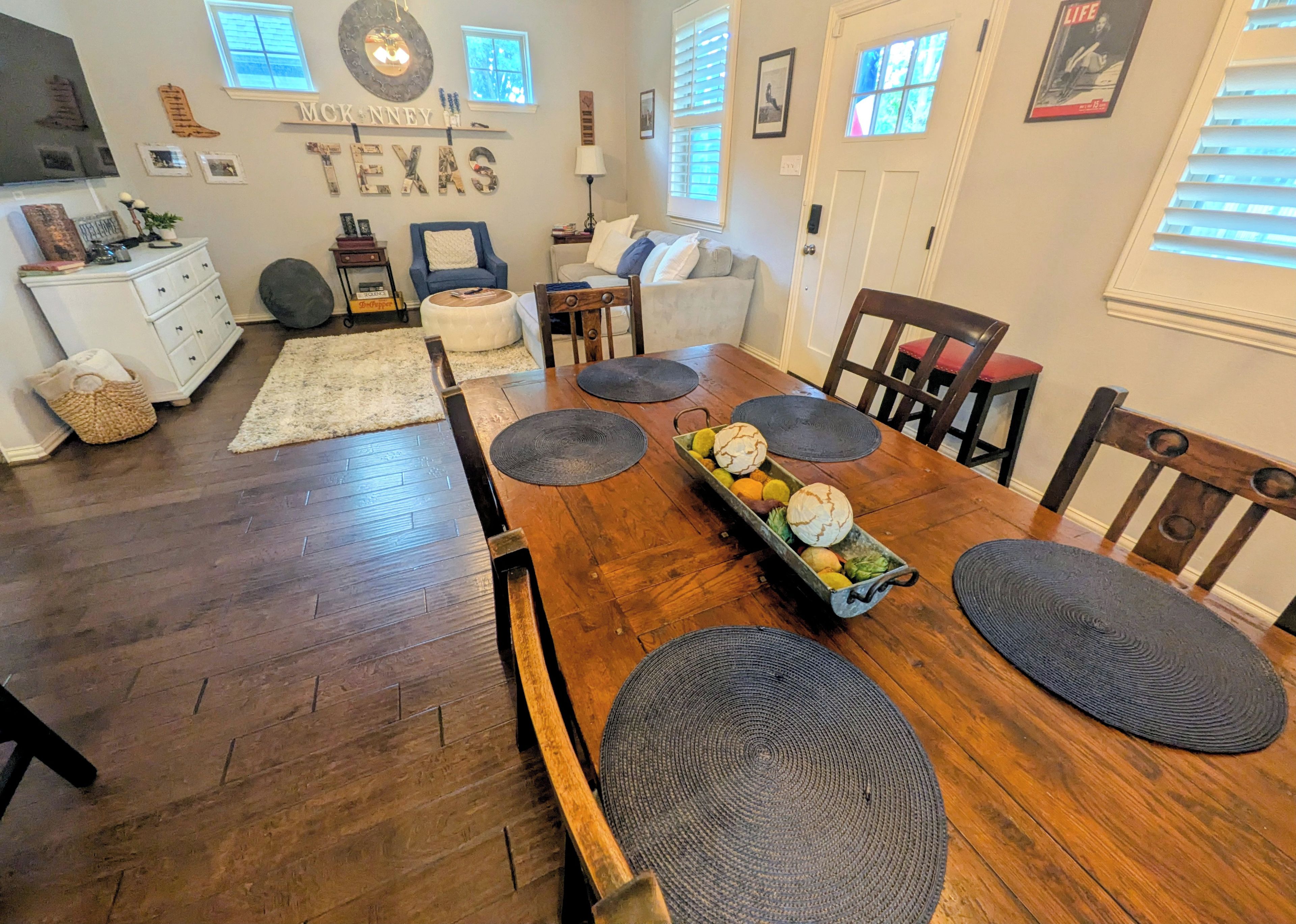 A dining area with a wooden table, chairs, and a fruit centerpiece.