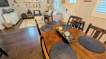 A dining area with a wooden table, chairs, and a fruit centerpiece.