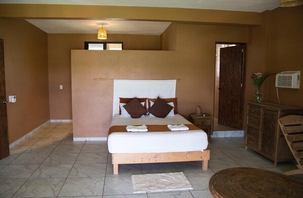 A bedroom with a bed, bedside tables, a wooden dresser, a chair, and a hanging light fixture. - Beachfrontguesthouse (Puerto Escondido)