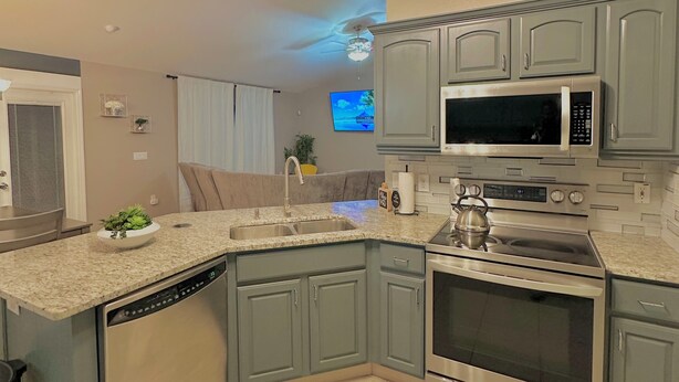 A modern kitchen with a built-in dishwasher, stainless steel appliances, and a ceiling fan. - Located Midway Orlando & Daytona Beach, Pet Friendly, Fenced Yard, 2 Car Garage (Deltona)