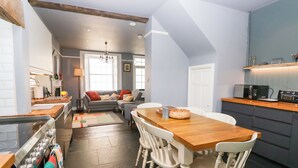 Una cocina moderna con comedor, que presenta una mesa de madera, sillas blancas y un horno empotrado.
