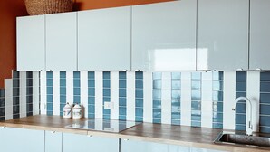 Een moderne keuken met lichtblauwe kastjes, een houten aanrecht en een achterwand met blauwe tegels.