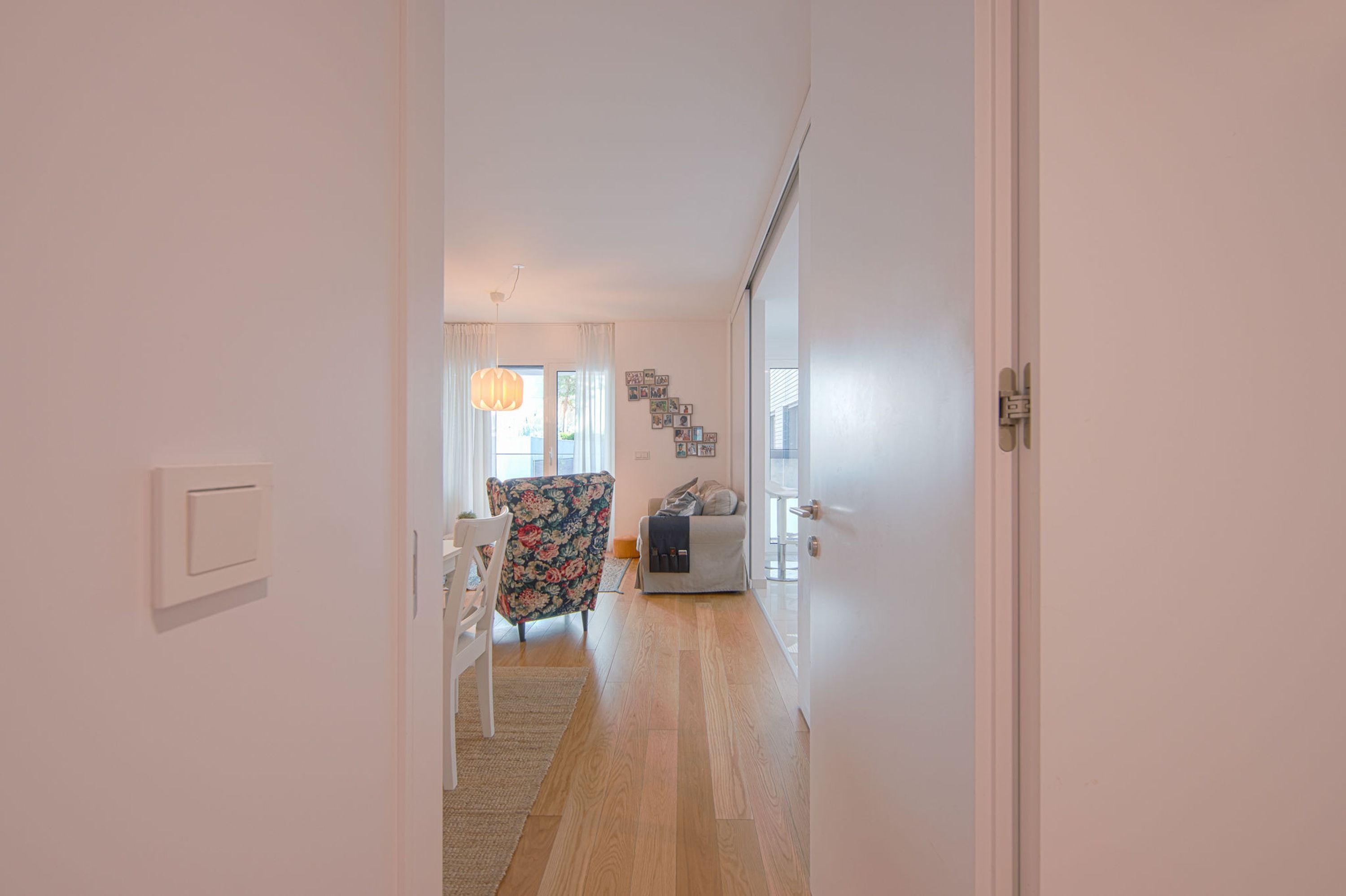 Un couloir avec une porte blanche, un fauteuil à motifs floraux, un canapé et un escalier menant à une autre pièce.