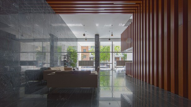 Eine moderne Lobby mit Marmorboden, einer Couch und einer Wand mit Holzverkleidung.