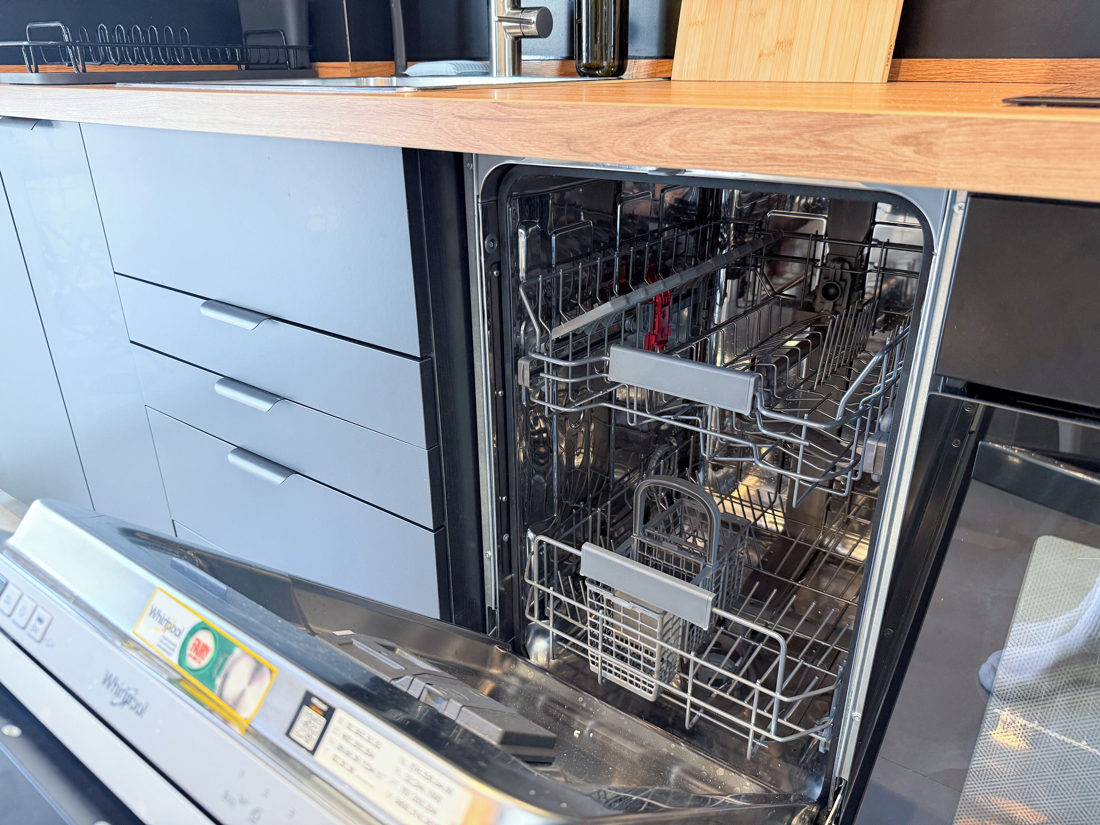 Una cocina moderna con lavavajillas, electrodomésticos de acero inoxidable y encimeras de madera.