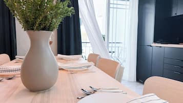 A dining table with a vase of green plants, neatly arranged cutlery, and striped napkins.