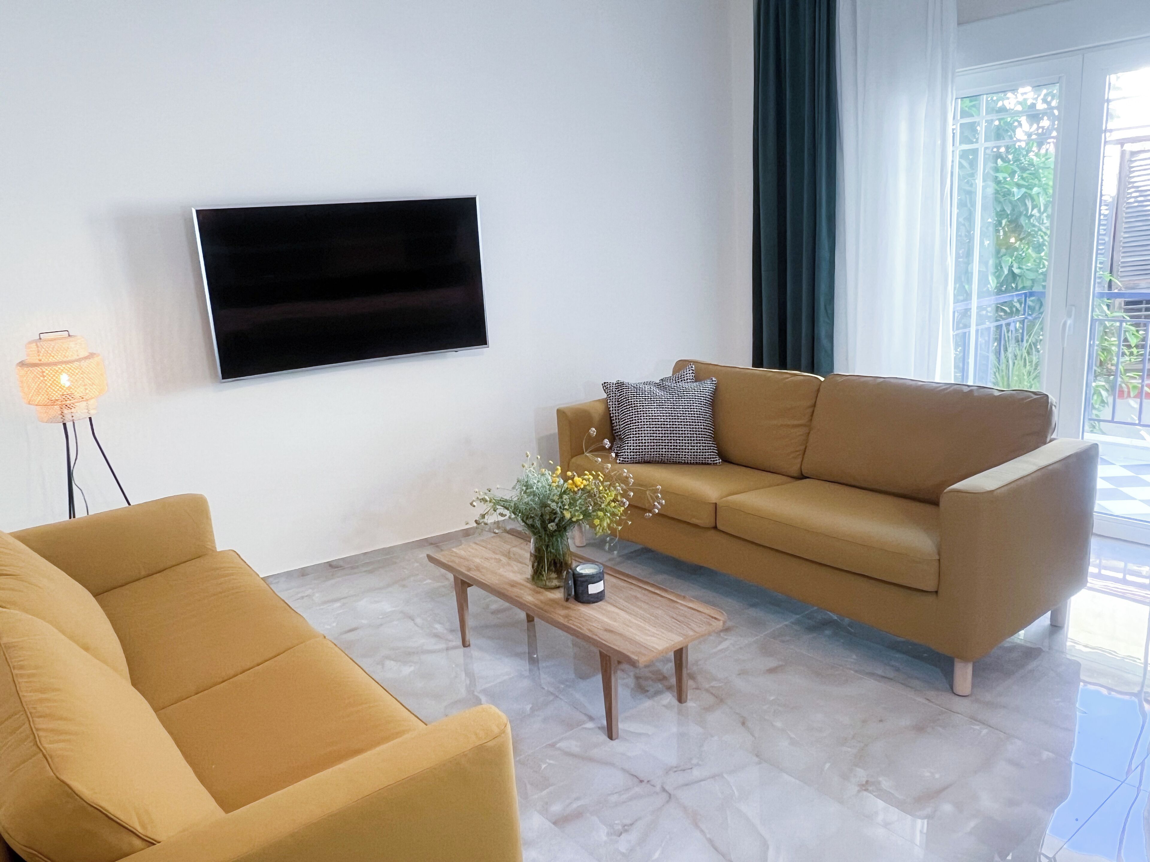 Un salon avec un canapé, une table basse et un téléviseur fixé au mur.