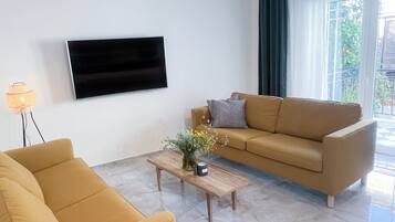 Un salon avec un canapé, une table basse et un téléviseur fixé au mur.