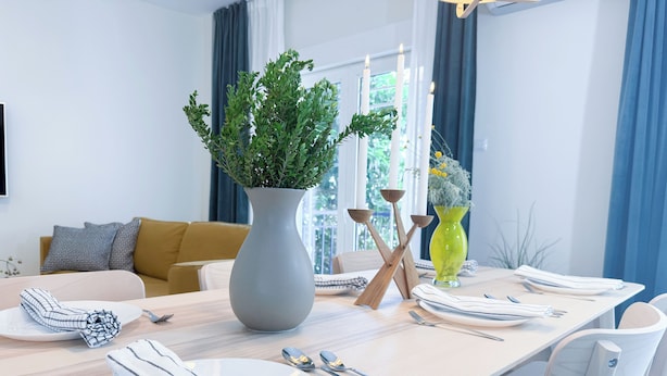 A dining area with a long table set for four, a grey vase with green foliage, and a yellow vase with flowers. - Central and Fully-Equipped (Kavala)